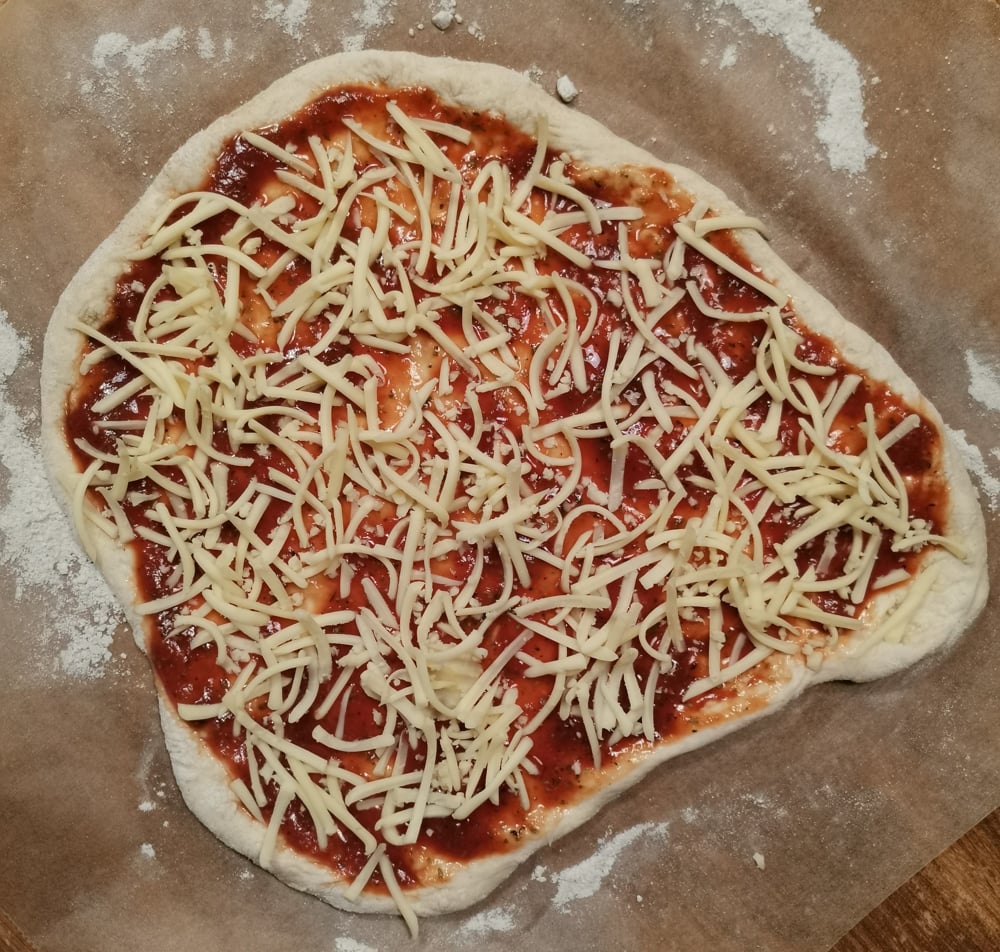 Pizzateig mit Soße und Käse belegt